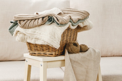 Panier en osier rempli de linge sur un tabouret en bois