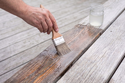 Application de sel d'oseille sur une terrasse en bois.