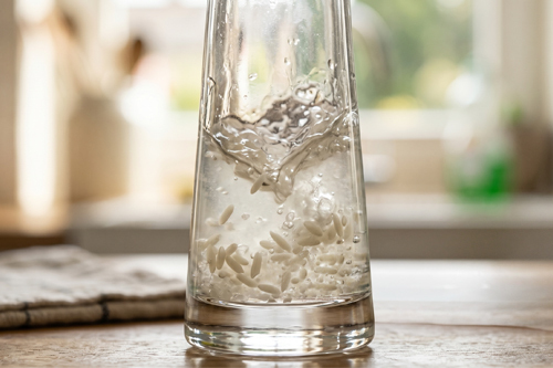 Nettoyage mécanique du fond d'un vase étroit avec du riz et du sel.